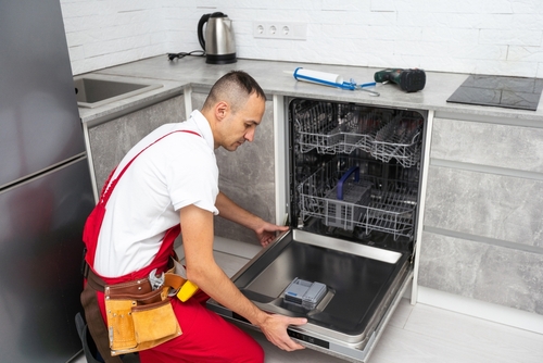 Young,Repairman,Service,Worker,Repairing,Dishwasher,Appliance,In,Kitchen